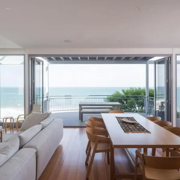 Architectural dining area with timber floors and panoramic ocean views in an Austinmer home by Simpson and Co Projects.