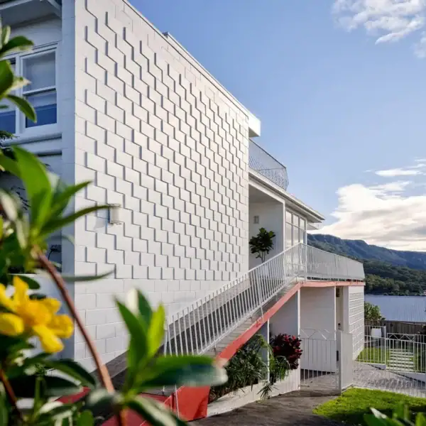multi level coastal home with white masonry wing and red architectural stairs