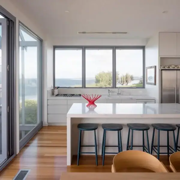 Modern gourmet kitchen with stone benchtops and ocean views in an Austinmer home by Simpson and Co Projects.