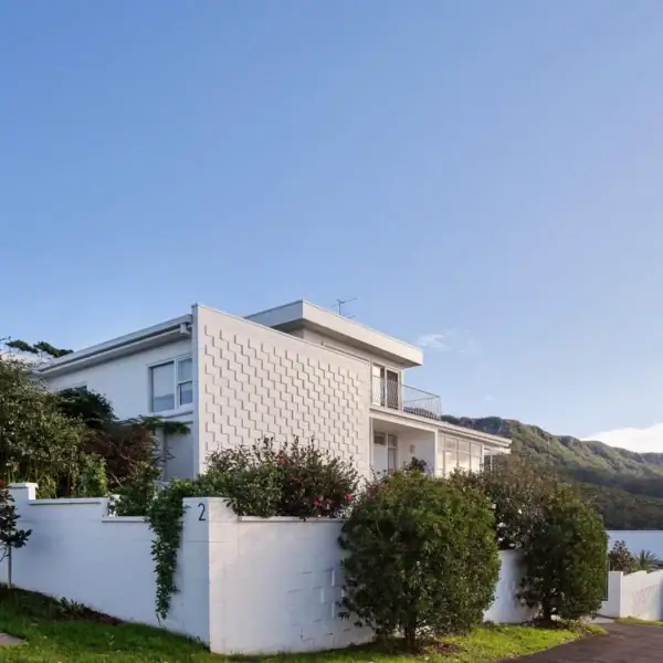 multi level modern coastal home with white breeze block facade and street side landscaping Title