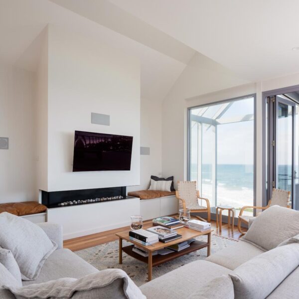 Minimalist architectural living room with a white fireplace and bespoke joinery in Austinmer by Simpson and Co Projects.