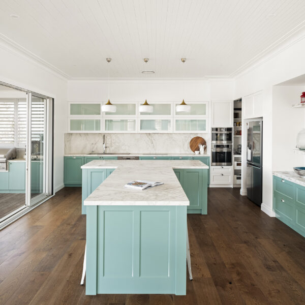 Coastal kitchen with marble island bench, mint cabinetry, glass-fronted upper cupboards and timber flooring at Wombarra No. 3.