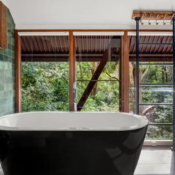 modern freestanding black bathtub with forest views and green handmade tiles Austinmer