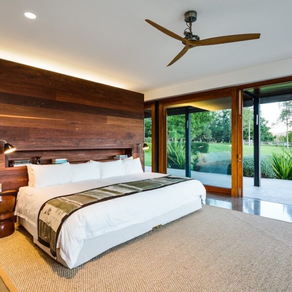 Architect-designed bedroom at Ooralba Estate featuring a timber feature wall, neutral bedding, and full-height glazing built by Simpson & Co in Kangaroo Valley.