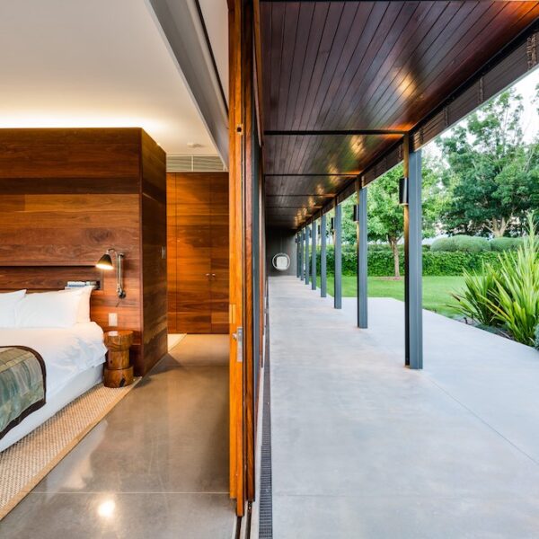 Timber-lined internal corridor at Ooralba Estate with full-height glass, polished concrete flooring, and views to the surrounding Kangaroo Valley landscape.