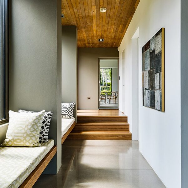 Architect-designed hallway at Ooralba Estate featuring timber ceiling lining, artwork, and a built-in window seat, constructed by Simpson & Co in Kangaroo Valley.