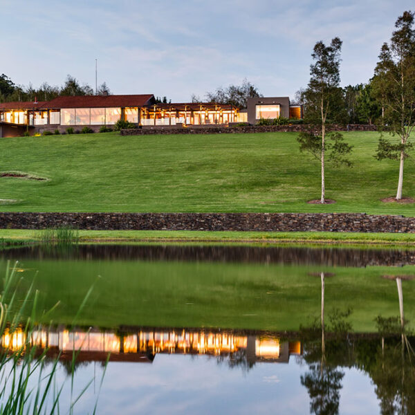 Landscape at Ooralba Estate with water reflection, rolling grassland, and distant residence, designed by Spirit Level Designs and built by Simpson & Co in Kangaroo Valley.