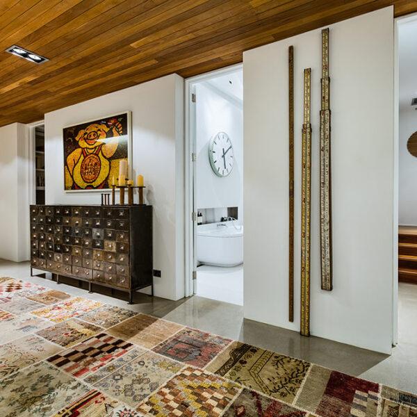 Architect-designed ensuite corridor at Ooralba Estate featuring timber ceiling lining, custom joinery, and a patterned rug, built by Simpson & Co in Kangaroo Valley.