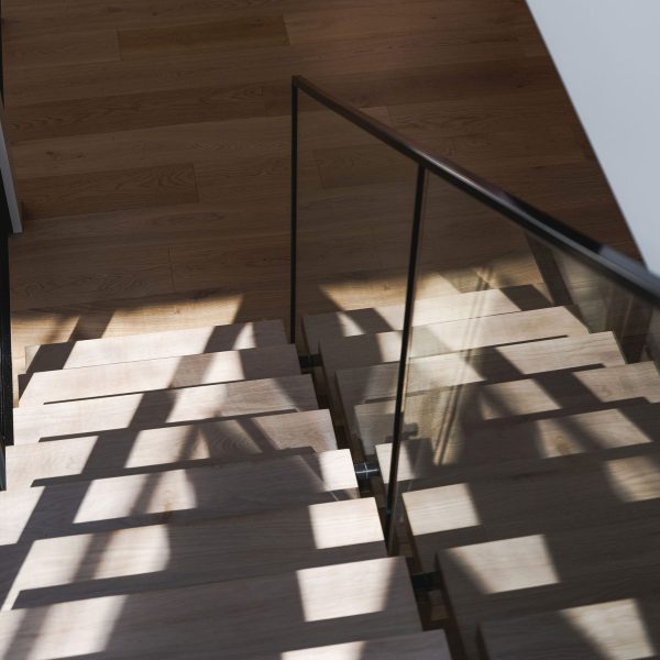 Light and shadow across timber stair and floor in Stanwell Park coastal custom home.