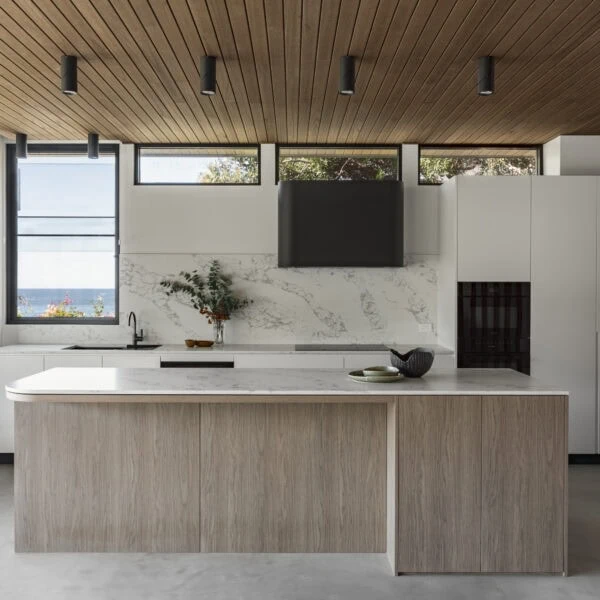 Contemporary kitchen in Stanwell Park No.3 featuring a stone island, timber ceiling and natural light.