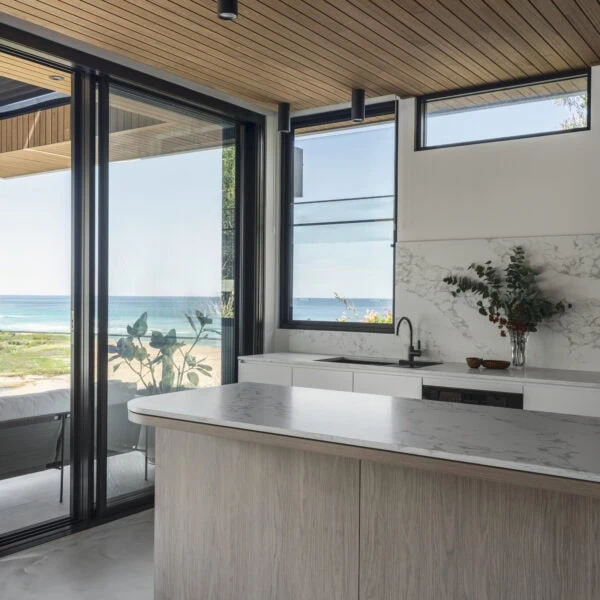 Kitchen in Stanwell Park No.3 with stone island, timber ceiling and views across the coastline.