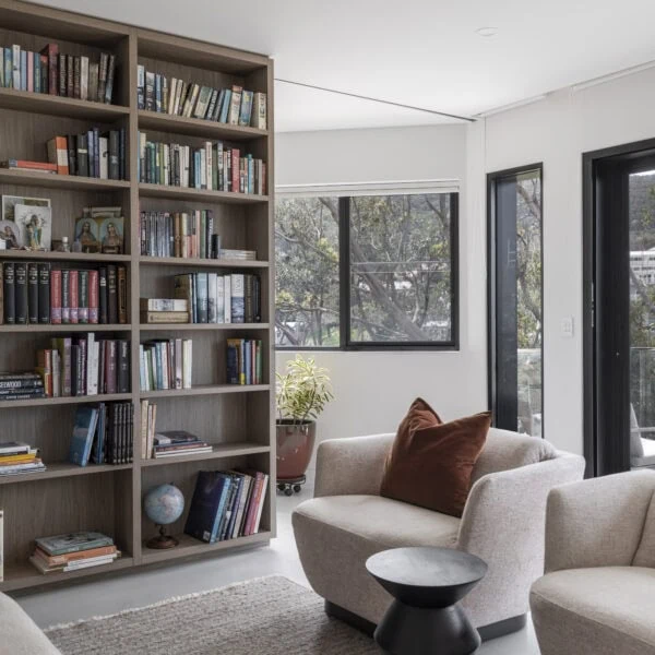 Living room with custom library shelving, lounge seating and natural light in Stanwell Park No.3.