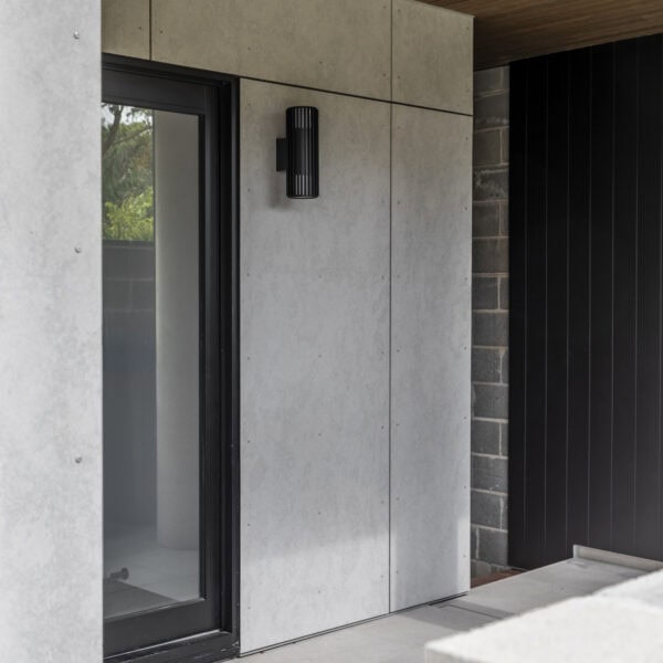 Covered front entry to Stanwell Park No.3 featuring concrete cladding, timber soffit and recessed entry door.