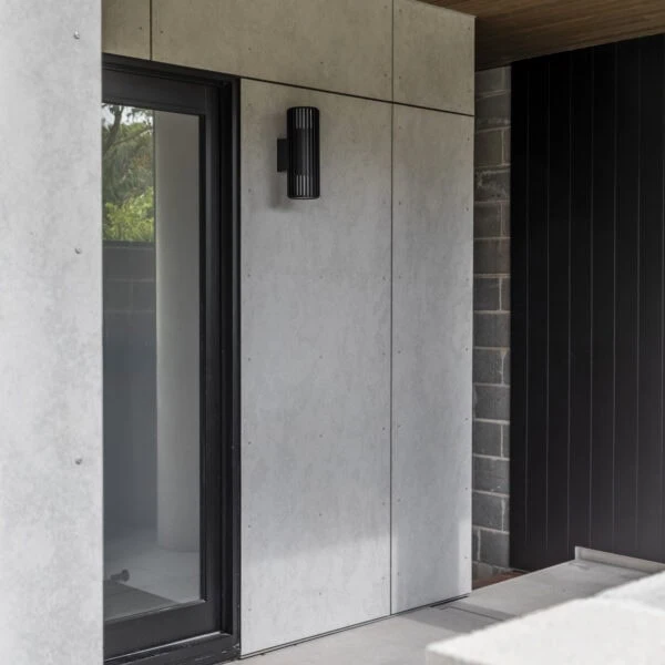 Covered front entry to Stanwell Park No.3 featuring concrete cladding, timber soffit and recessed entry door.