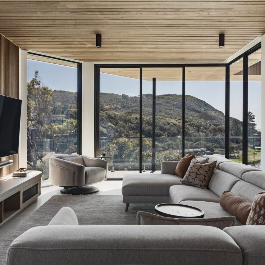 Open-plan living room in Stanwell Park No.3 with floor-to-ceiling glazing overlooking the surrounding landscape.