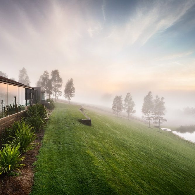 Architect-designed exterior façade at Ooralba Estate with timber and stone detailing, built by Simpson & Co and overlooking misty morning views across Kangaroo Valley.