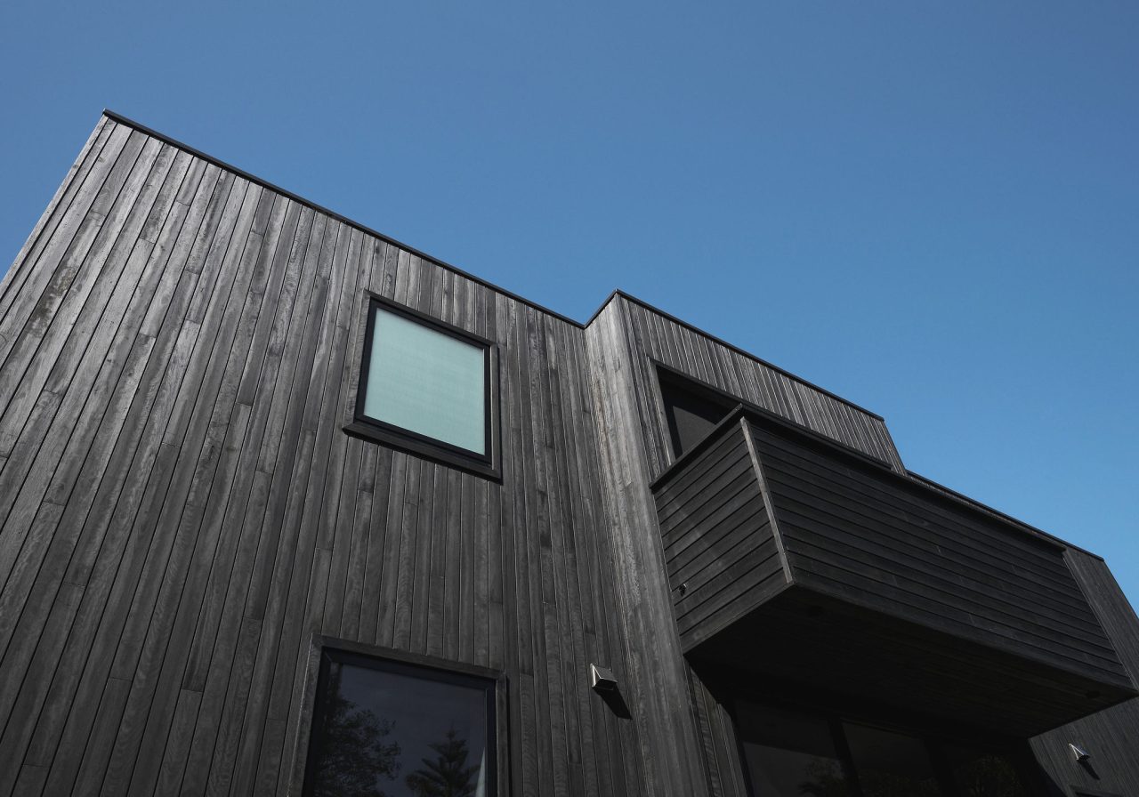 Glazed balcony detail on coastal custom home in Stanwell Park with vertical timber cladding.