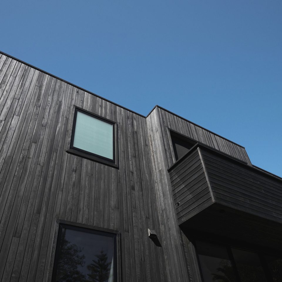 Glazed balcony detail on coastal custom home in Stanwell Park with vertical timber cladding.